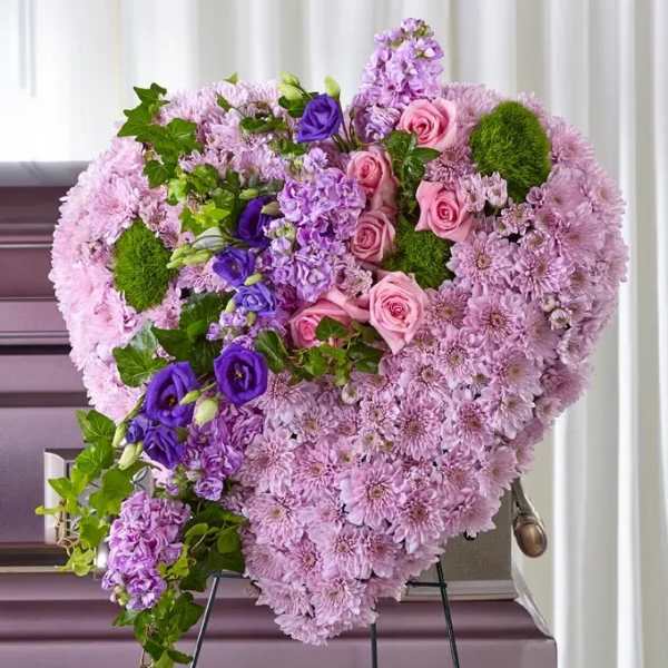 Heart-shaped floral arrangement of pink and purple flowers on an easel