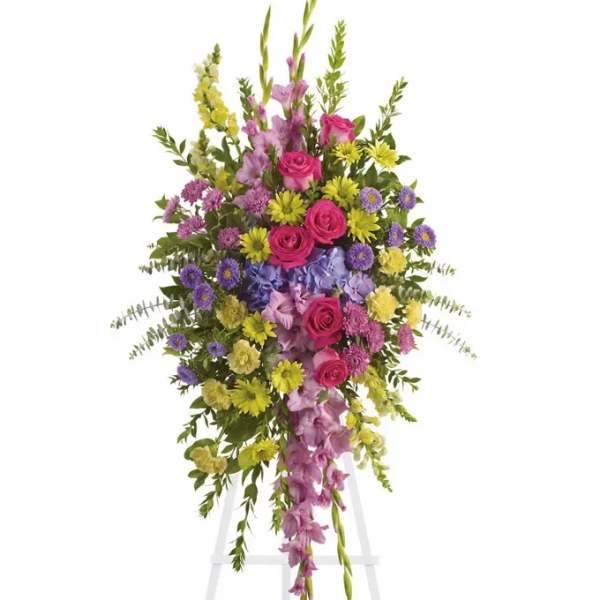 Tall standing floral spray with pink, purple, and yellow flowers on an easel