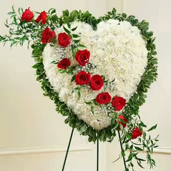 Heart-shaped white floral spray with red roses on a stand