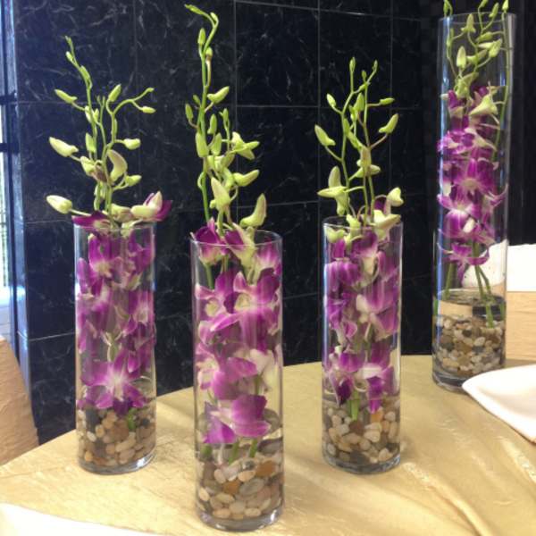 Purple orchids in tall glass vases with pebbles