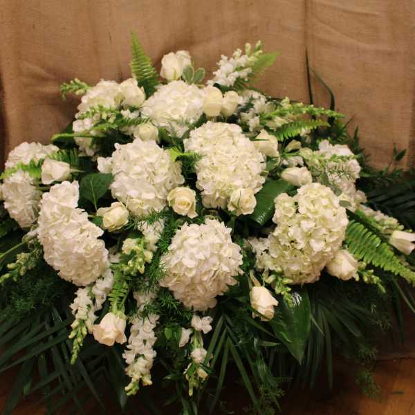 Large white floral arrangement with hydrangeas and roses