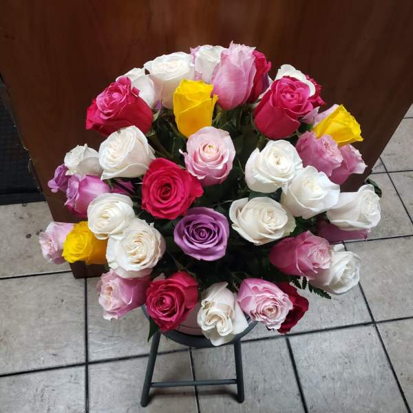 Bouquet of multicolored roses in a round container