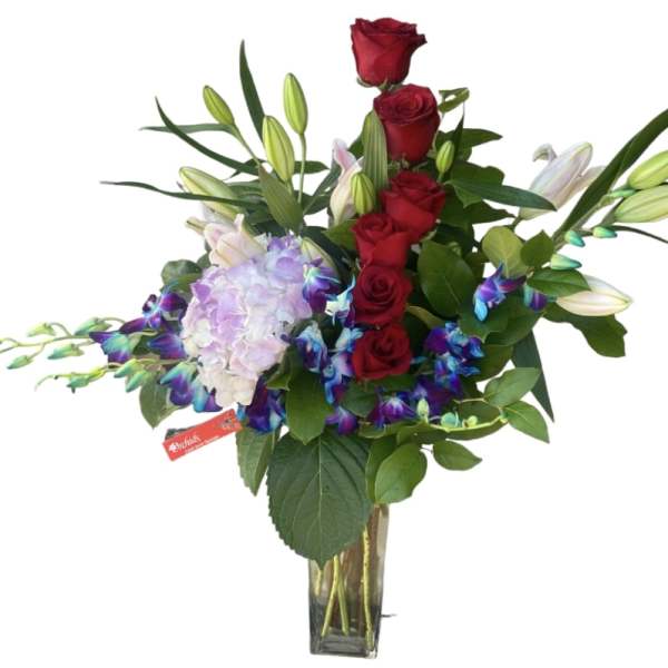 Red roses, lilies, and lavender hydrangea in a glass vase