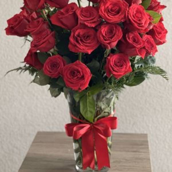 Bouquet of red roses in a clear glass vase with a red ribbon