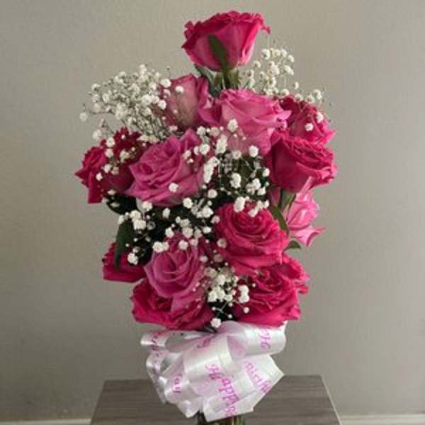 Pink rose bouquet in a glass vase with baby's breath and a ribbon bow