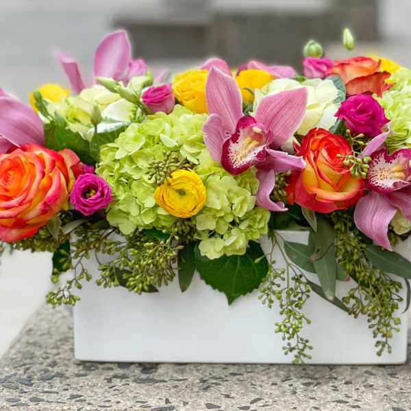 Colorful floral arrangement in a white rectangular vase