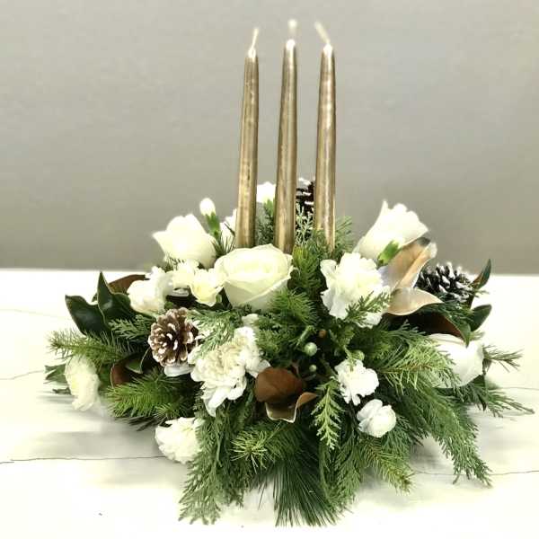 White floral centerpiece with gold taper candles and pinecones