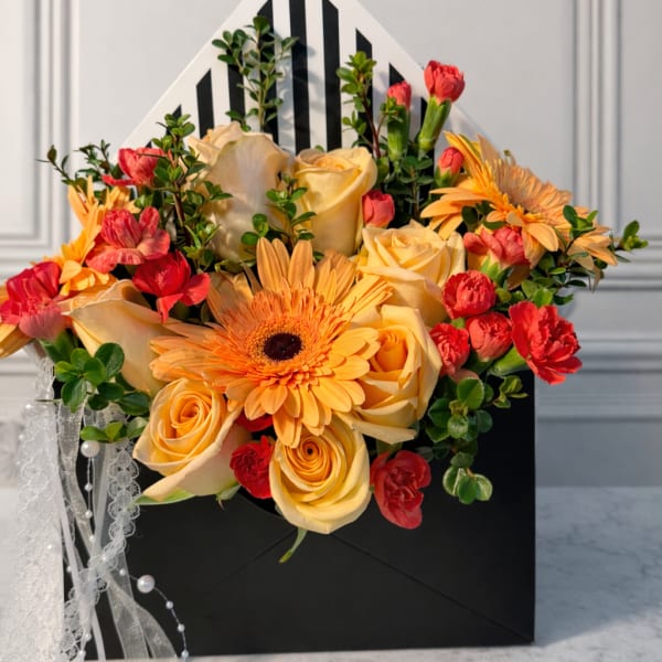 Bouquet of yellow roses, orange gerbera daisies, and red carnations in a black gift box