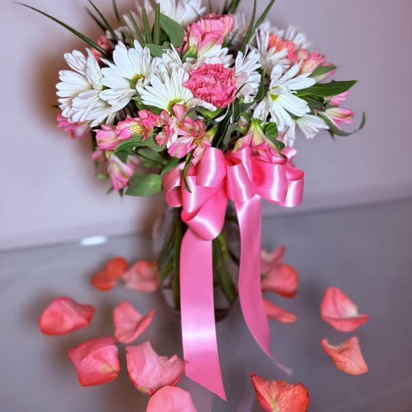 Pink and white bouquet in a glass vase with a satin ribbon