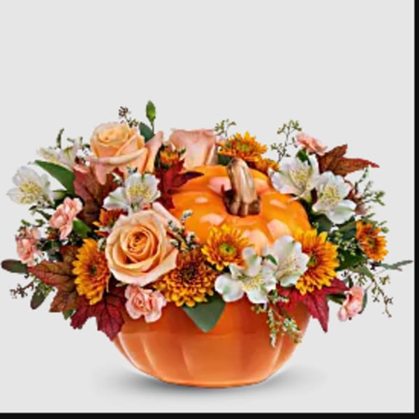 Pumpkin-shaped container with peach roses and orange flowers