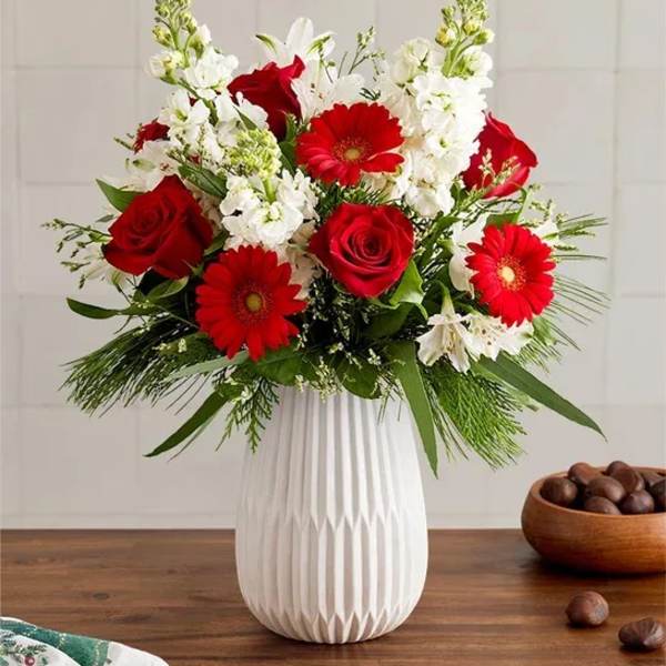 Red roses and gerbera daisies in a white vase