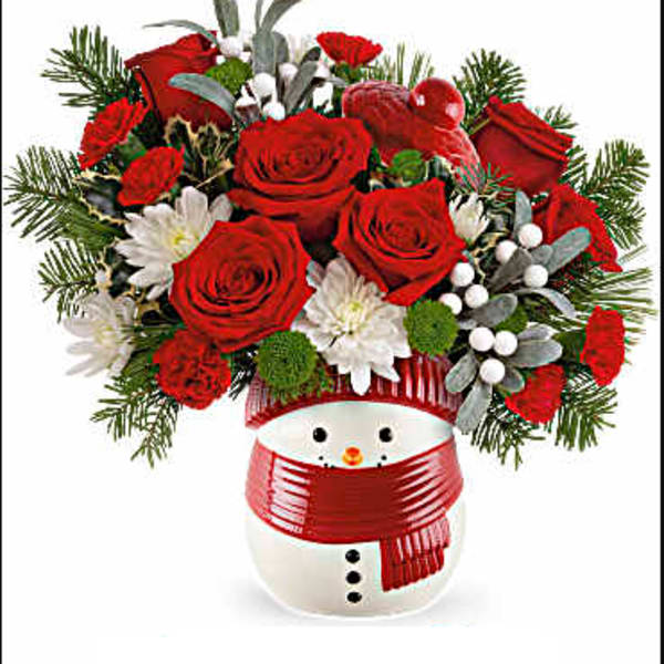 Red roses and white flowers arranged in a snowman vase with a red scarf