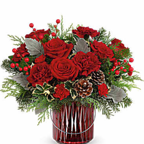 Red roses arranged in a red glass vase with pinecones and berries