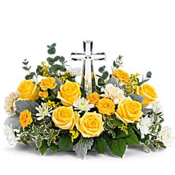 Yellow roses and white flowers arranged around a clear glass cross