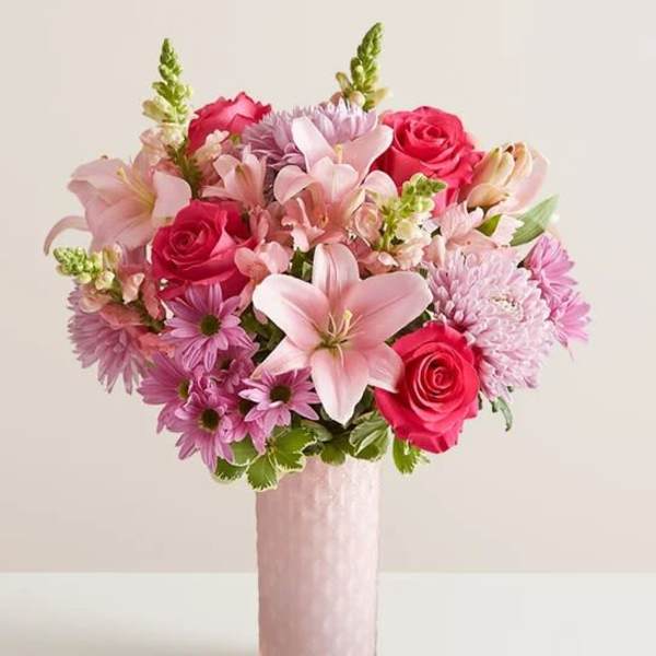 Pink and lavender bouquet with roses and lilies in a tall pink vase