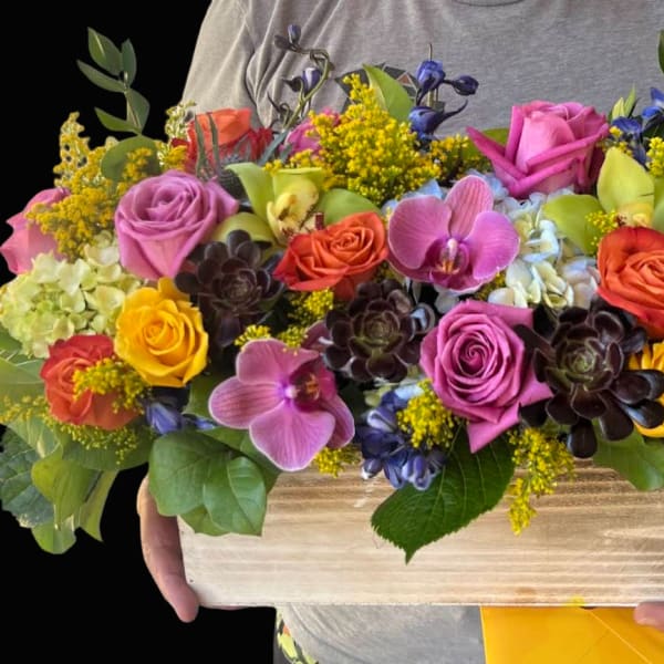 Colorful mixed bouquet in a wooden box with roses and orchids