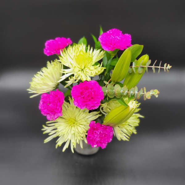 Pink carnations and pale green spider mums in a small vase