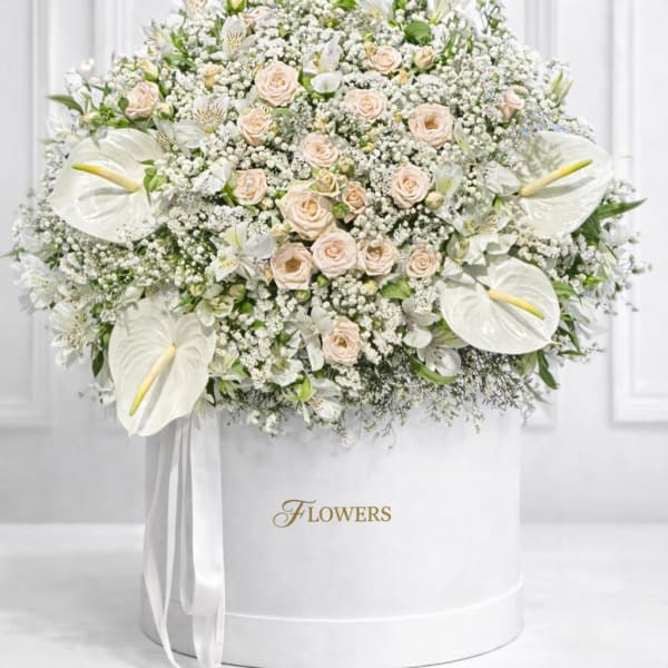 White floral arrangement with roses and calla lilies in a round box