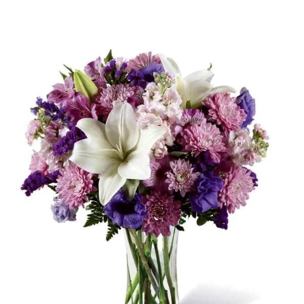 Purple and pink mixed bouquet with white lilies in a clear glass vase