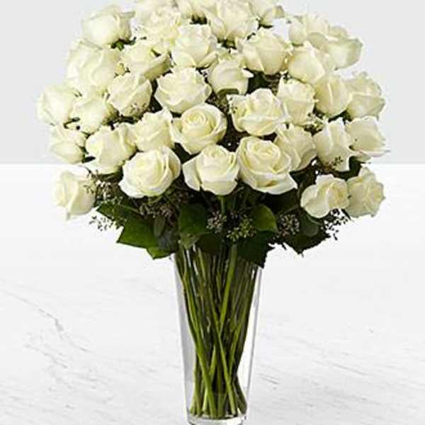 Tall clear vase filled with a large bouquet of white roses