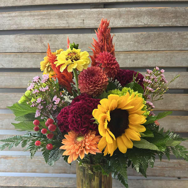 Colorful mixed bouquet in a glass vase with sunflowers and dahlias
