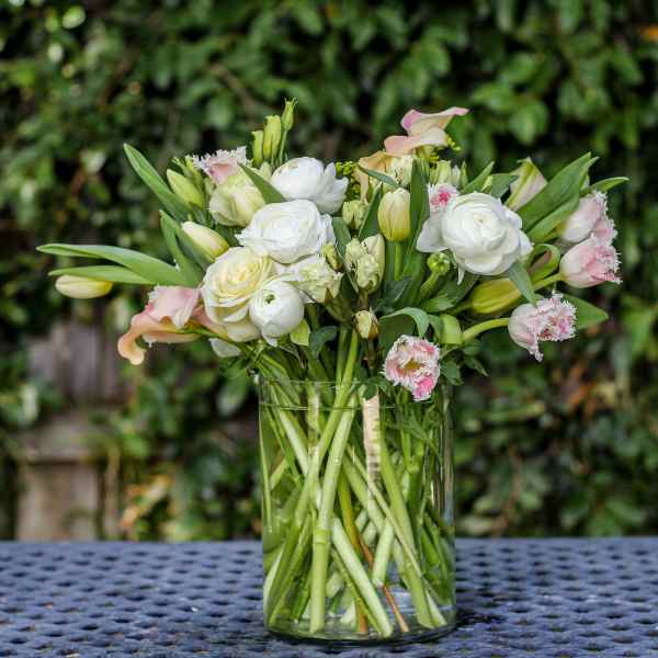 White and pale pink flowers arranged in a clear glass vase