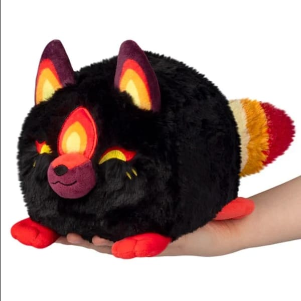 Black plush fox toy with colorful ears and tail, resting on a hand