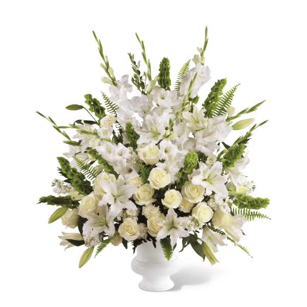 Tall white arrangement with lilies, roses, and gladiolus in a white pedestal vase