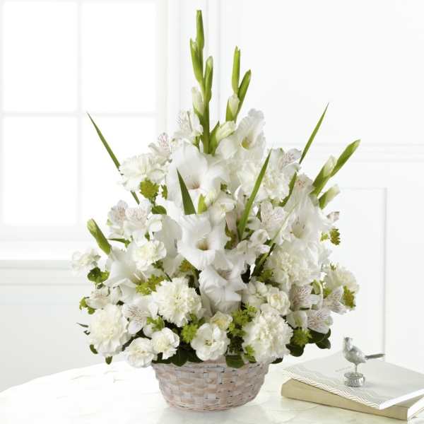 White floral arrangement in a woven basket with tall green spikes