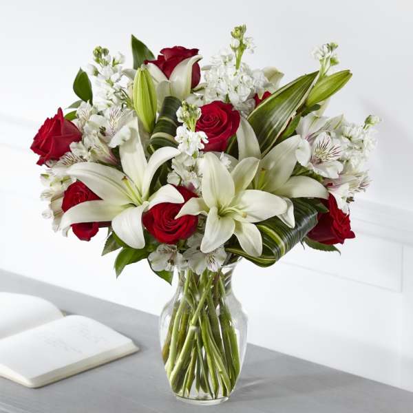 Bouquet of red roses and white lilies in a clear glass vase