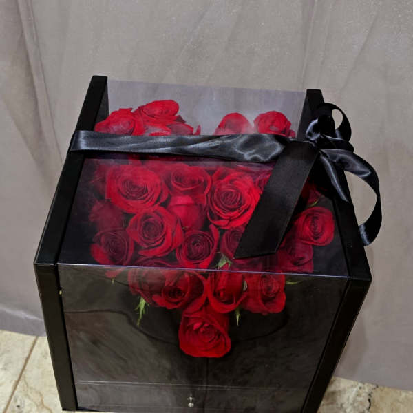 Red roses arranged in a black gift box with a satin ribbon