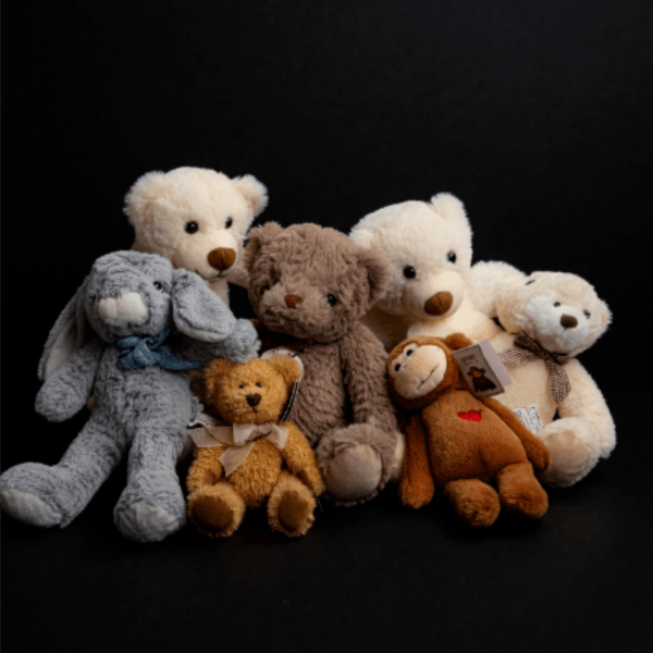 Assorted teddy bears and plush animals posed against a black background