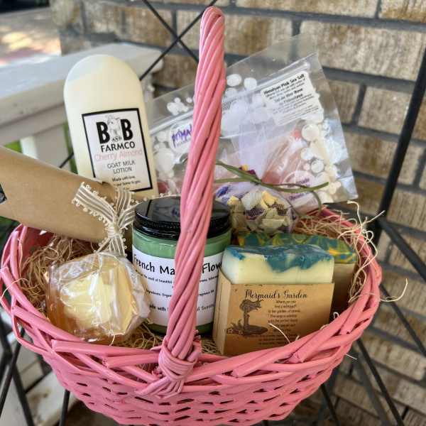 Pink basket filled with soaps, lotion, and a small dried lavender bouquet
