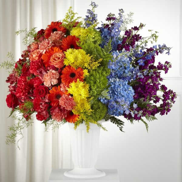 Colorful mixed flower arrangement in a white pedestal vase