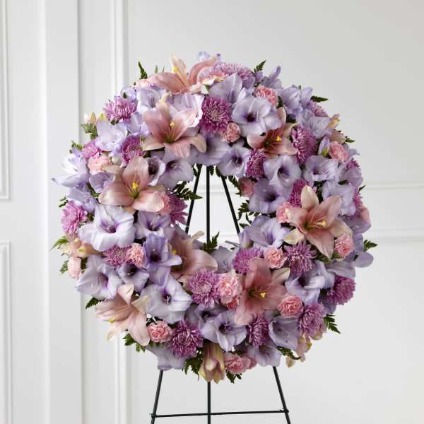 Large wreath of lavender and pink lilies, carnations, and mums on a metal easel stand