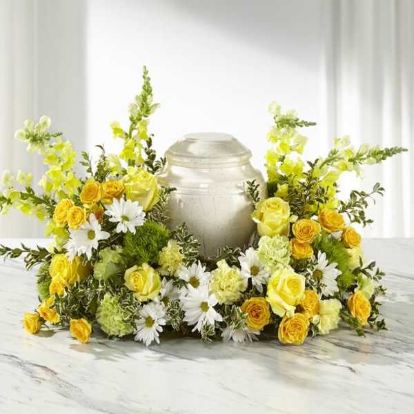 Yellow roses and white daisies arranged around a silver urn