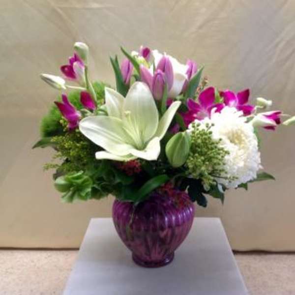 Bouquet of white lilies and purple tulips in a purple glass vase