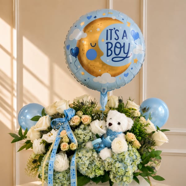 Blue baby boy balloon over white roses and hydrangeas with a teddy bear