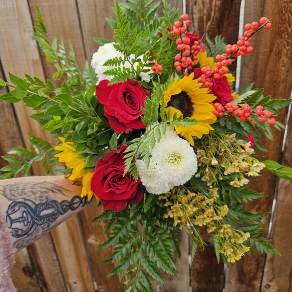 Bouquet of red roses, sunflowers, and white mums with berry accents