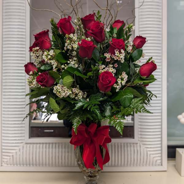 Red rose arrangement in a glass vase with a red ribbon