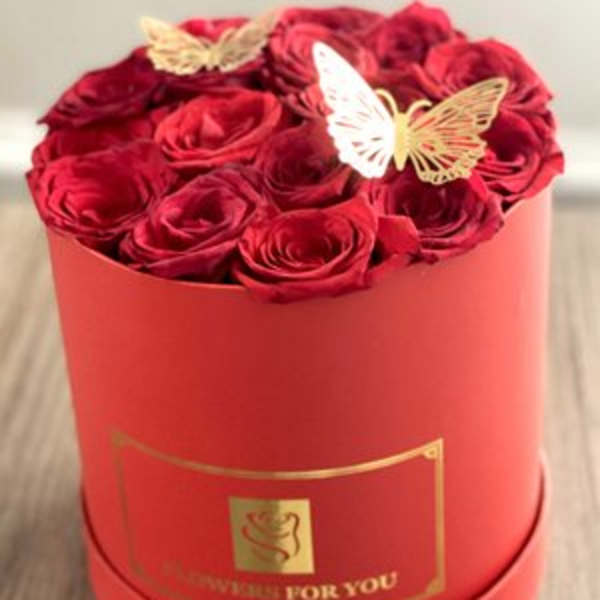 Red roses arranged in a round red box with butterfly decorations