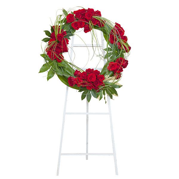 Standing wreath of red roses on a white easel