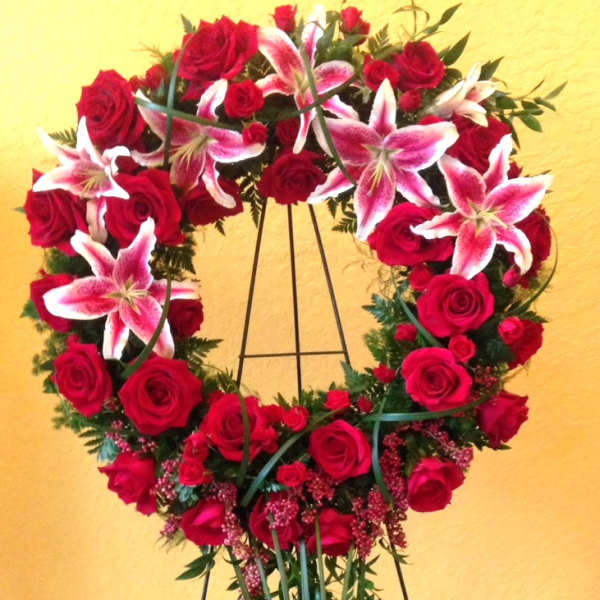 Heart-shaped wreath of red roses and pink lilies on a stand