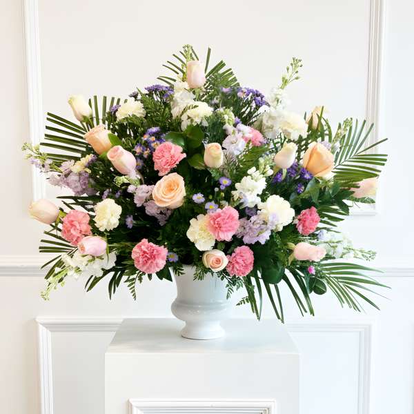 Large mixed flower arrangement in a white urn vase