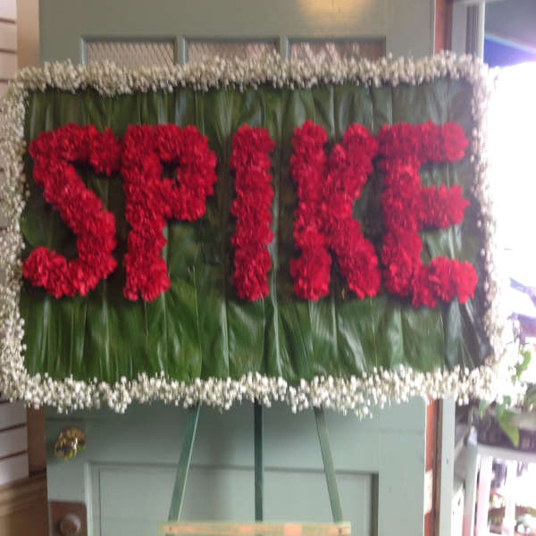 Red floral spray spelling "SPICE" on a green leaf background