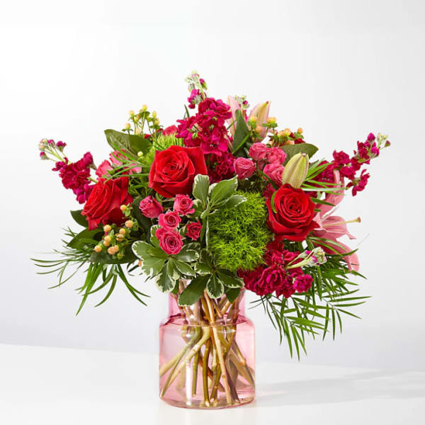 Bouquet of red and pink flowers in a pink glass vase