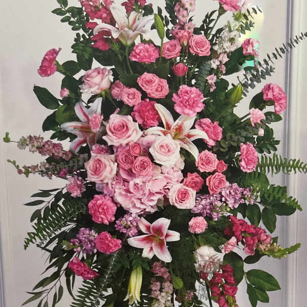 Tall pink floral standing spray with roses, lilies, and carnations on an easel