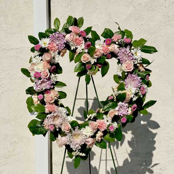 Heart-shaped floral wreath with pink and white flowers on a stand