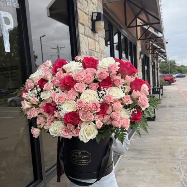 Large bouquet of pink and white roses in a black hatbox