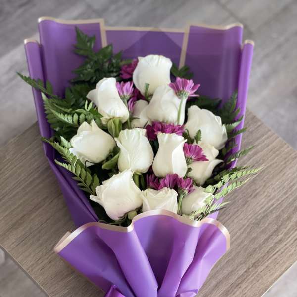 Bouquet of white roses and purple daisies wrapped in purple paper